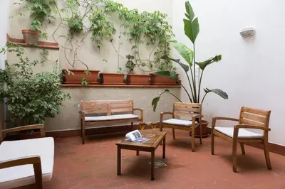 a patio with chairs and tables and potted plants at White and Sea Villa fronte mare a Mondello Addaura in Palermo