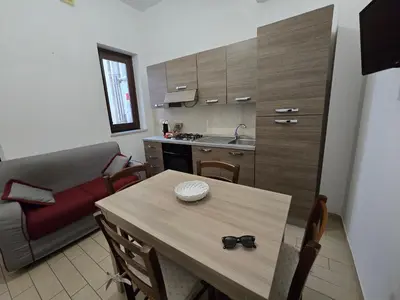 a living room with a table and a couch and a kitchen at Guglie del centro in Palermo