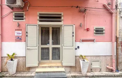 a pink building with a door and two plants at Casa Toledo in Partinico