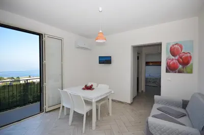 a white dining room with a white table and chairs at Appartamenti da Clarissa in Macari