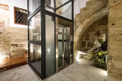 a glass elevator in a building with a stone wall at Quattro Canti Apartments in Palermo