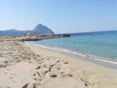 a beach with footprints in the sand and the ocean at Baglio Fontana in Castelluzzo
