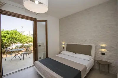 a bedroom with a bed and a balcony with a table at Cala di Ponente in Castelluzzo