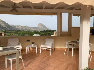 a patio with tables and chairs and a view of mountains at Cala di Ponente in Castelluzzo