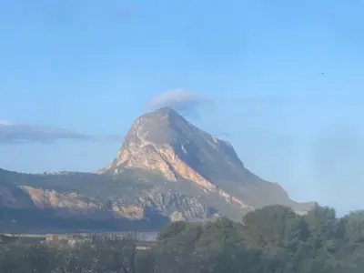 a mountain with smoke coming out of it at Cala di Ponente in Castelluzzo