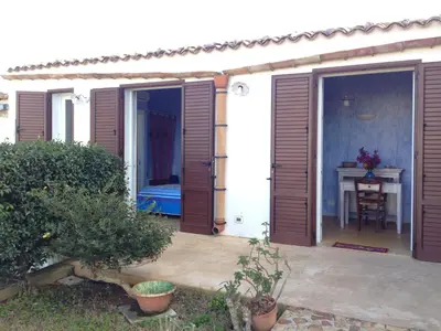 a patio with wooden doors and a table with a table at Villetta Degli Oleandri in Castellammare del Golfo