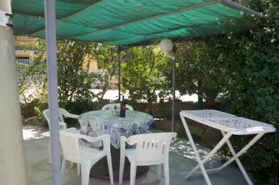 a table and chairs under a green umbrella at Casa Vacanza e Camera Fabiola in Castellammare del Golfo