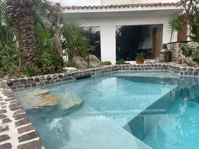 a swimming pool with blue water in front of a house at Villa Il Cappero in San Vito lo Capo