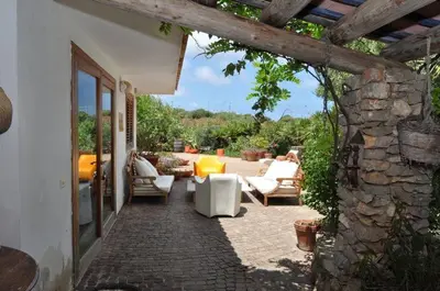 a patio with white furniture and a stone wall at Villa Il Cappero in San Vito lo Capo