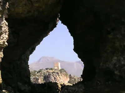 a view through a hole in a rock with a building in the background at Casa Vacanze La Terrazza Sul Golfo in Castellammare del Golfo