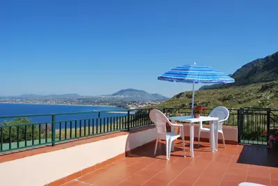 a balcony with a table and chairs and an umbrella at Casa Vacanze La Terrazza Sul Golfo in Castellammare del Golfo