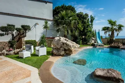 a swimming pool with a rock in a yard at Villa esclusiva Milazzo Annarita in Castellammare del Golfo