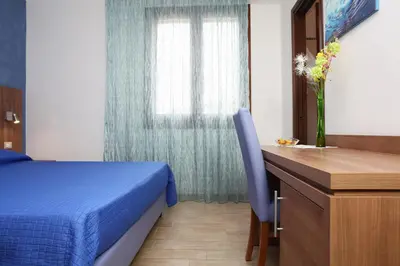 a bedroom with a bed and a desk and a window at Coralia Bed & Breakfast in San Vito lo Capo