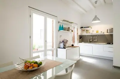 a white kitchen with a bowl of fruit on a table at Cassari UpArtments in Palermo