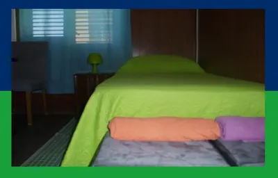 a bedroom with a bed and a chair and a table at Santa Oliva Homestay in Palermo