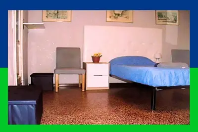 a bedroom with a blue bed and a chair at Santa Oliva Homestay in Palermo