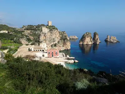 an island with a red house in the middle of the water at Villa Iris in Castellammare del Golfo