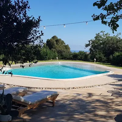 a swimming pool with a bench in front of it at Terre e Torri Country Resort in Lascari
