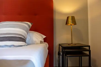 a bed with a red headboard and a lamp on a side table at Le Muse Mondello in Mondello