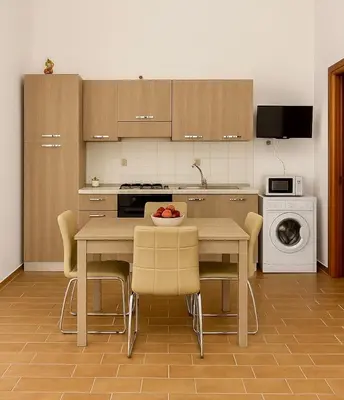 a kitchen with a table and chairs with a bowl of fruit on it at Il Glicine Appartamenti & Rooms in Castellammare del Golfo