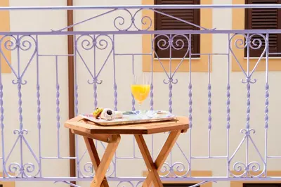 a table with a glass of orange juice on a balcony at Il Glicine Appartamenti & Rooms in Castellammare del Golfo