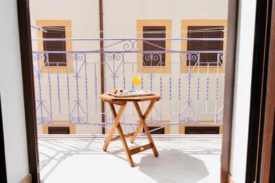 a table with a glass of wine on a balcony at Il Glicine Appartamenti & Rooms in Castellammare del Golfo