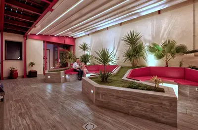 a person sitting in a room with red couches and plants at Hospitality Hotel in Palermo