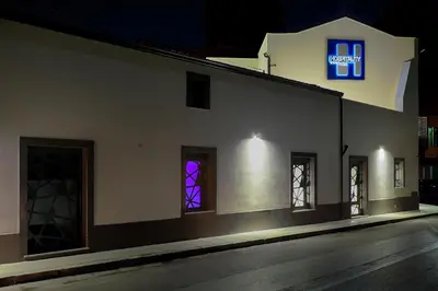 a white building with a neon sign on the side of it at Hospitality Hotel in Palermo