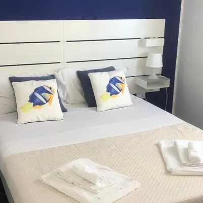 a bed with white pillows and blue and yellow pillows at Casa Vacanze Playa 54 in Castellammare del Golfo