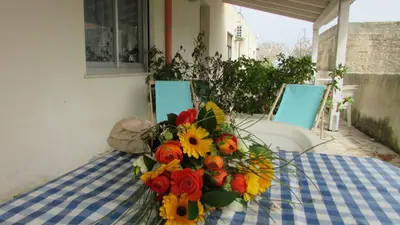 a bouquet of flowers on a table with two chairs at Appartamento Spiaggia Playa in Castellammare del Golfo