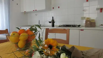 a kitchen with a table with a bowl of fruit at Appartamento Spiaggia Playa in Castellammare del Golfo