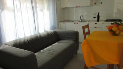a living room with a couch and a table and a kitchen at Appartamento Spiaggia Playa in Castellammare del Golfo