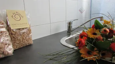 a counter with a sink with a bouquet of flowers at Appartamento Spiaggia Playa in Castellammare del Golfo
