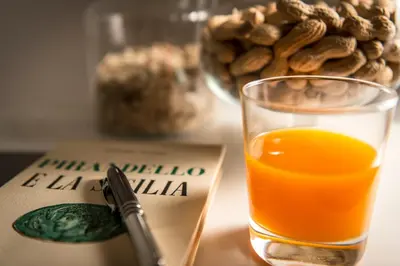 a glass of orange juice next to a book and a pen at Dimora Torremuzza in Palermo