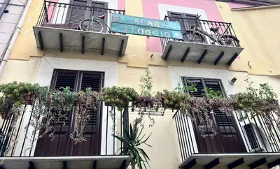 a building with potted plants and balconies on it at Bahalara Alloggio in Palermo