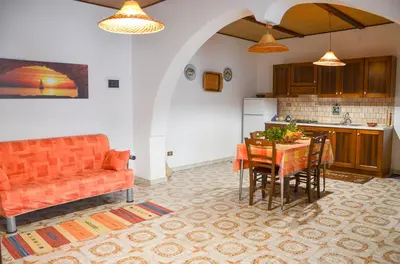 a kitchen with an orange couch and a table with chairs at La Grande Palma in Castelluzzo