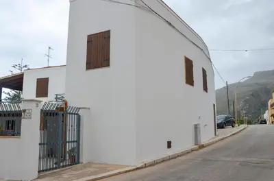 a white building with two windows on a street at La Grande Palma in Castelluzzo