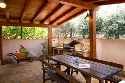 a patio with a wooden table and a kitchen at Alba Marina B&B in Castelluzzo