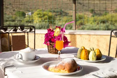 a table with two plates of food and a drink at Alba Marina B&B in Castelluzzo