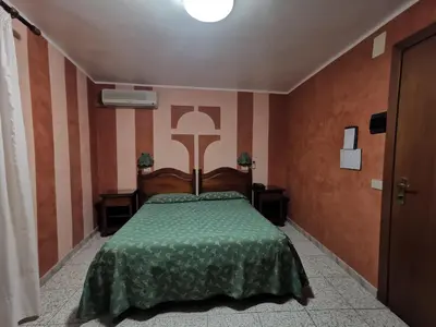 a bedroom with a bed with a green comforter at Hotel Cortese in Palermo