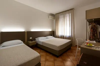 a hotel room with two beds and a table with a bowl of fruit at Sun Garden in San Vito lo Capo