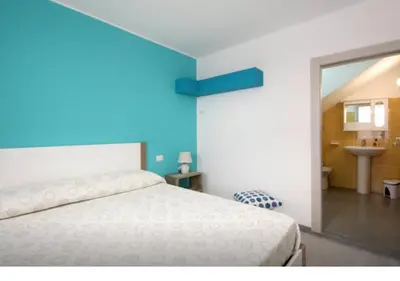 a bedroom with a white bed and a blue wall at Rainbow in Castellammare del Golfo