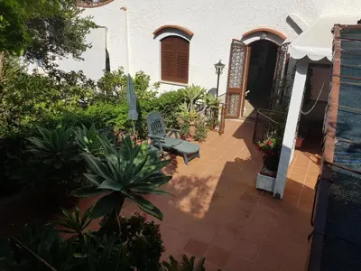 a patio with a bench in front of a house at Villa del Golfo Urio with swimming pool shared by the two apartments it is essential to have a car in Santa Flavia