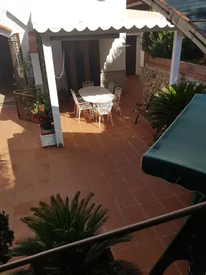a patio with a table and chairs and an umbrella at Villa del Golfo Urio with swimming pool shared by the two apartments it is essential to have a car in Santa Flavia