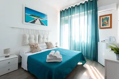 a white bedroom with a blue bed with shoes on it at Mondello House Eraclea in Mondello