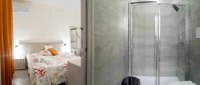 a small bathroom with a shower and a bed at Monte Monaco B&B in San Vito lo Capo