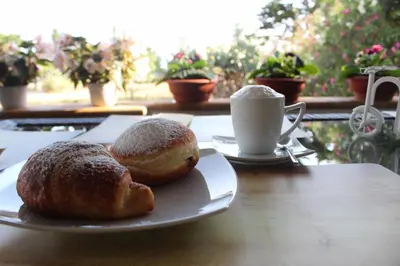 two pastries on a plate on a table with a cup of coffee at Monte Monaco B&B in San Vito lo Capo