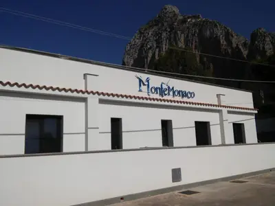 a white building with a mountain in the background at Monte Monaco B&B in San Vito lo Capo