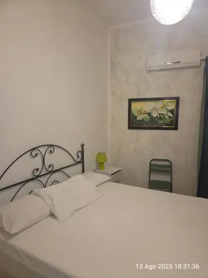 a bedroom with a white bed and a picture on the wall at Nostra casa rooms in Palermo