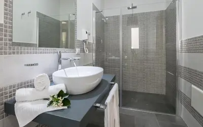 a bathroom with a sink and a glass shower at Pharos in San Vito lo Capo
